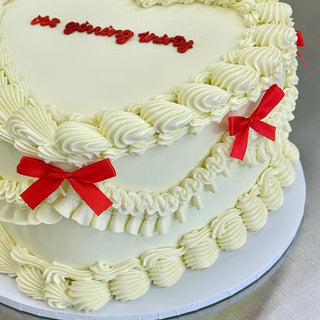 White ruffled vintage cake with red writing
